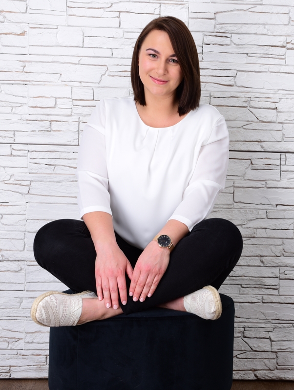 Sarah Sturmbauer sitzt im Schneidersitz vor einer weißen gekachelten Wand